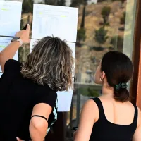 Μητέρα και υποψήφια στις Πανελλαδικές εξετάσεις κοιτάζουν σε πίνακα τις βάσεις εισαγωγής