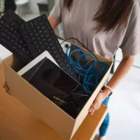 Γυναίκα κρατάει κούτα με υπολογιστή και πληκτρολόγιο