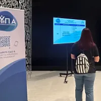 Γυναίκα περπατάει σε διάδρομο με το λογότυπο της ΔΥΠΑ