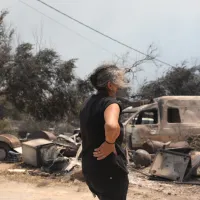 Γυναίκα κοιτάζει τις καταστροφές από τη φωτιά στο Πόρτο Γερμενό