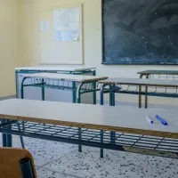 Αίθουσα σχολείου με άδεια θρανία, πίνακα και αντισηπτικό επάνω σε θρανίο