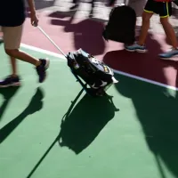 Μαθητής σέρνει τσάντα με ροδάκια σε προαύλιο σχολείου