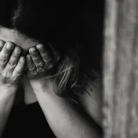 Γυναίκα κρατάει το πρόσωπό της μέσα στα χέρια της