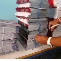 Εκπαιδευτικός κόβει με ψαλίδι ταινία που κρατάει σχολικά βιβλία για να τα μοιράσει σε μαθητές