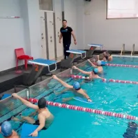 Γυμναστής σε κολυμβητήριο κάνει μάθημα σε παιδιά που είναι μέσα στην πισίνα