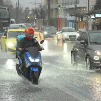 Αυτοκίνητα και μηχανές στον δρόμο ενώ ρίχνει δυνατή βροχή και ο δρόμος έχει νερά