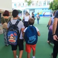 Μαθητές με τις τσάντες τους συνοδεύονται από πατέρα προς το σχολείο