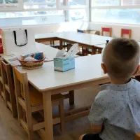 Παιδί νηπιαγωγείου κάθεται σε θρανίο με πλάτη στην κάμερα