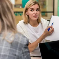 Εκπαιδευτικός δείχνει σε μαθήτρια σημείωση σε τετράδιο 