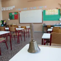 Τάξη σχολείου με κουδούνι πάνω σε θρανίο