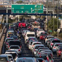 Φωτογραφία αυτοκινήτων σε ελληνικό δρόμο εν κινήσει, με φόντο αστικό τοπίο, που σχετίζεται με θέματα τελών κυκλοφορίας και ελέγχων οχημάτων από την ΑΑΔΕ