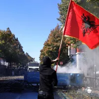 A protester waves an Albanian flag during clashes in Tirana, Albania, Wednesday, Oct. 14, 2026, joining a demonstration organized by the Flamingo protest movement demanding the resignation of Prime Minister Edi Rama. (AP Photo/Hameraldi Agolli)