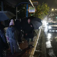 Κόσμος με ομπρέλες σε στάση λεωφορείου στην Αττική ενώ ειναι καταιγίδα σε ελέλιξη