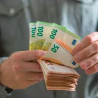 Άνδρας μετράει χαρτονομίσματα με ευρώ