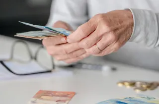 Γυναίκα συνταξιούχους μετράει χρήματα συνταξιοδότησης – αλλαγές στη φορολογία για πρόωρη σύνταξη και ΤΕΑ