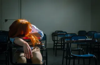 Κουρασμένη δασκάλα έχει ξαπλώσει πάνω σε θρανίο τάξης