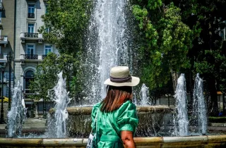 Γυναίκα περπατάει μπροστά από συντριβάνι εν μέσω καύσωνα