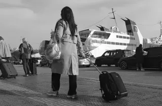 Γυναίκα εκπαιδευτικός αναπληρώτρια με βαλίτσα στο χέρι ετοιμάζει να μπει σε καράβι