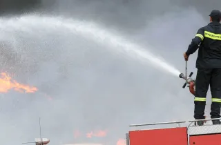 Πυροσβέστης πάνω σε όχημα της Πυροσβεστικής σβήνει με μάνικα φωτιά 