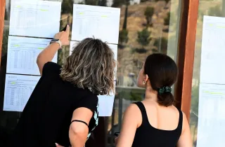 Μητέρα και υποψήφια στις Πανελλαδικές εξετάσεις κοιτάζουν σε πίνακα τις βάσεις εισαγωγής