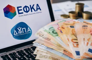 Λογότυπο ΕΦΚΑ και ΔΥΠΑ σε υπολογιστή και στο πληκτρολόγιο φαίνονται χρήματα