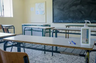 Αίθουσα σχολείου με άδεια θρανία, πίνακα και αντισηπτικό επάνω σε θρανίο