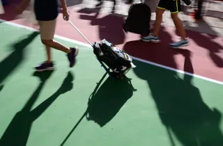 Μαθητής σέρνει τσάντα με ροδάκια σε προαύλιο σχολείου
