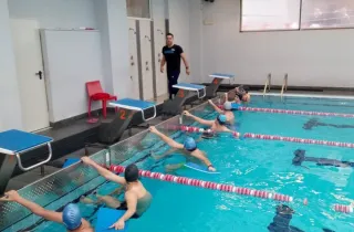 Γυμναστής σε κολυμβητήριο κάνει μάθημα σε παιδιά που είναι μέσα στην πισίνα