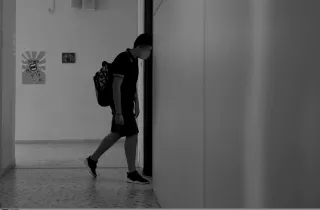 Μαθητής περπατάει μέσα σε σχολείο σε ασπρόμαυρη φωτογραφία