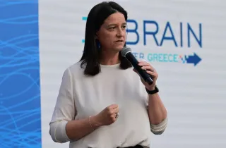 Η υπουργός Εργασίας Νίκη Κεραμέως σε ομιλία της και στο φόντο το λογότυπο του Rebrain Greece