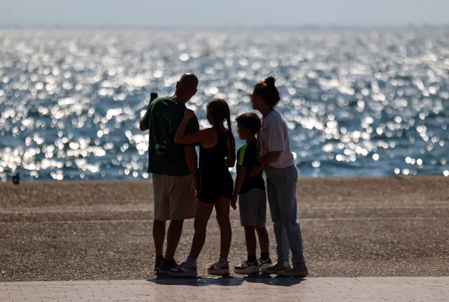 Οικογένεια που θα πάρει το έκτακτο επίδομα παιδιού κοιτάζει τη θάλασσα αγκαλιά