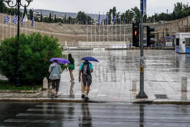 Άνθρωποι με ομπρέλες στο Καλλιμάρμαρο ενώ βρέχει στην Αττική
