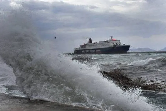 Πλοίο της γραμμής περνάει μπροστά από λιμάνι ενώ κύμα σκάει στην προβλήτα