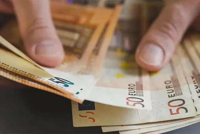 Ανδρικά χέρια που μετρούν χαρτονομίσματα ευρώ, σε άρθρο που αφορά τα ποσά και τις πληρωμές των συντάξεων
