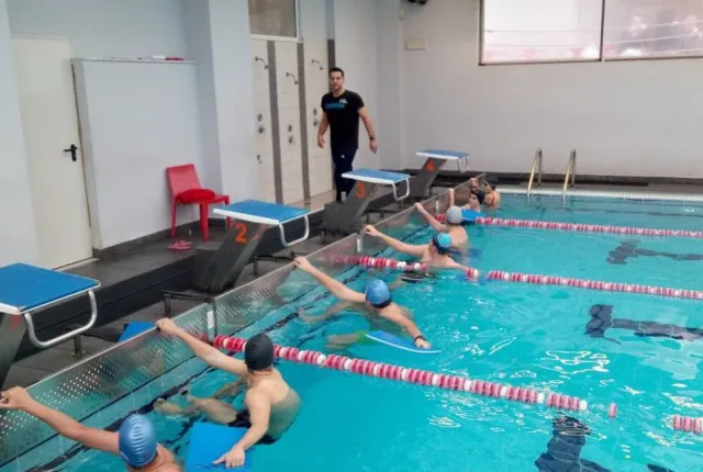 Γυμναστής σε κολυμβητήριο κάνει μάθημα σε παιδιά που είναι μέσα στην πισίνα