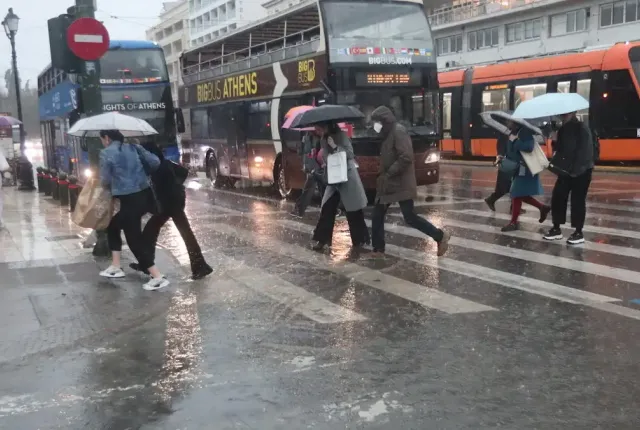 Άνθρωποι με ομπρέλες στον δρόμο τρέχουν από βροχή και κακοκαιρία