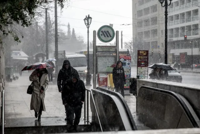 Κόσμος περπατάει μέσα στην κακοκαιρία σε σταθμό του Μετρό στην Αθήνα