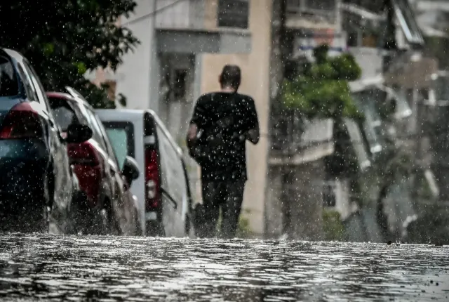 Άνδρας περπατάει μέσα στην καταιγίδα την ώρα που βρέχει