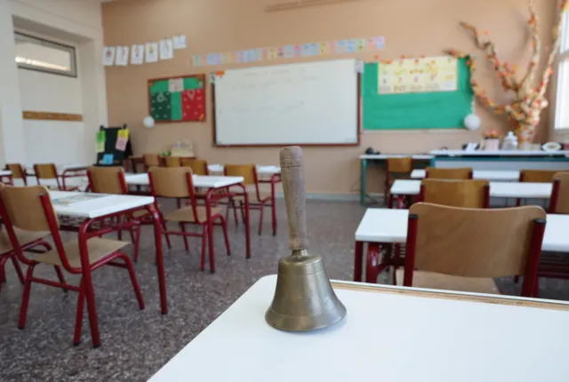 Τάξη σχολείου με κουδούνι πάνω σε θρανίο