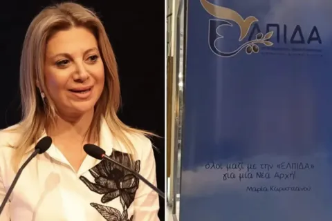 Η Μαρία Καρυστιανού με φόντο το λογότυπο του κόμματός της «Ελπίδα»