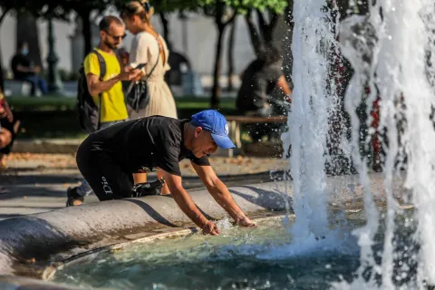 Άνδρας δροσίζεται εν μέσω καύσωνα στο σιντριβάνι στο Σύνταγμα