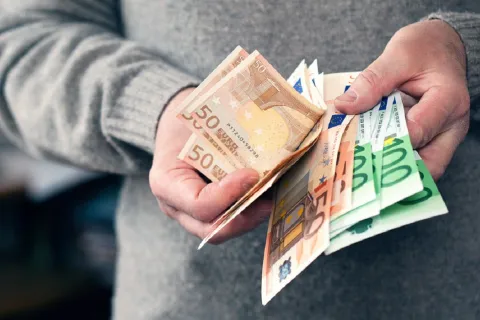 Άνδρας μετράει χρήματα και ευρώ με τα χέρια του