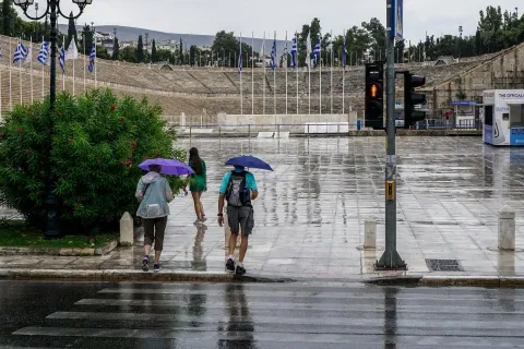 Άνθρωποι με ομπρέλες στο Καλλιμάρμαρο ενώ βρέχει στην Αττική