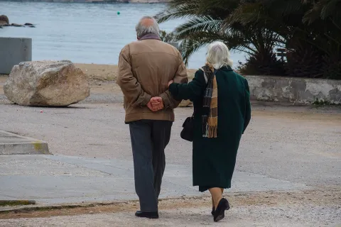 Συνταξιούχοι περπατάνε στον δρόμο με φόντο τη θάλασσα