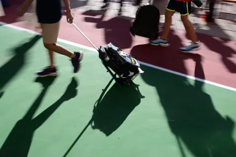 Μαθητής σέρνει τσάντα με ροδάκια σε προαύλιο σχολείου