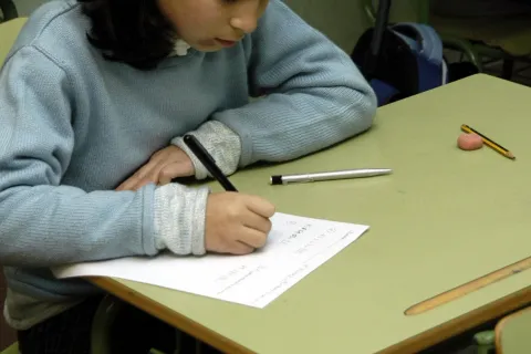 Μαθήτρια σε σχολείο γράφει με χαρτί