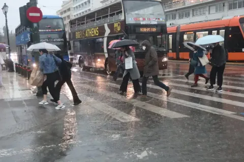 Άνθρωποι με ομπρέλες στον δρόμο τρέχουν από βροχή και κακοκαιρία