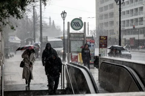 Κόσμος περπατάει μέσα στην κακοκαιρία σε σταθμό του Μετρό στην Αθήνα