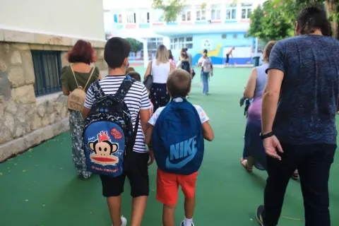 Μαθητές με τις τσάντες τους συνοδεύονται από πατέρα προς το σχολείο