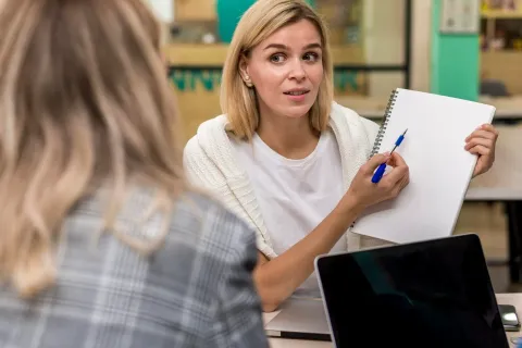 Εκπαιδευτικός δείχνει σε μαθήτρια σημείωση σε τετράδιο 